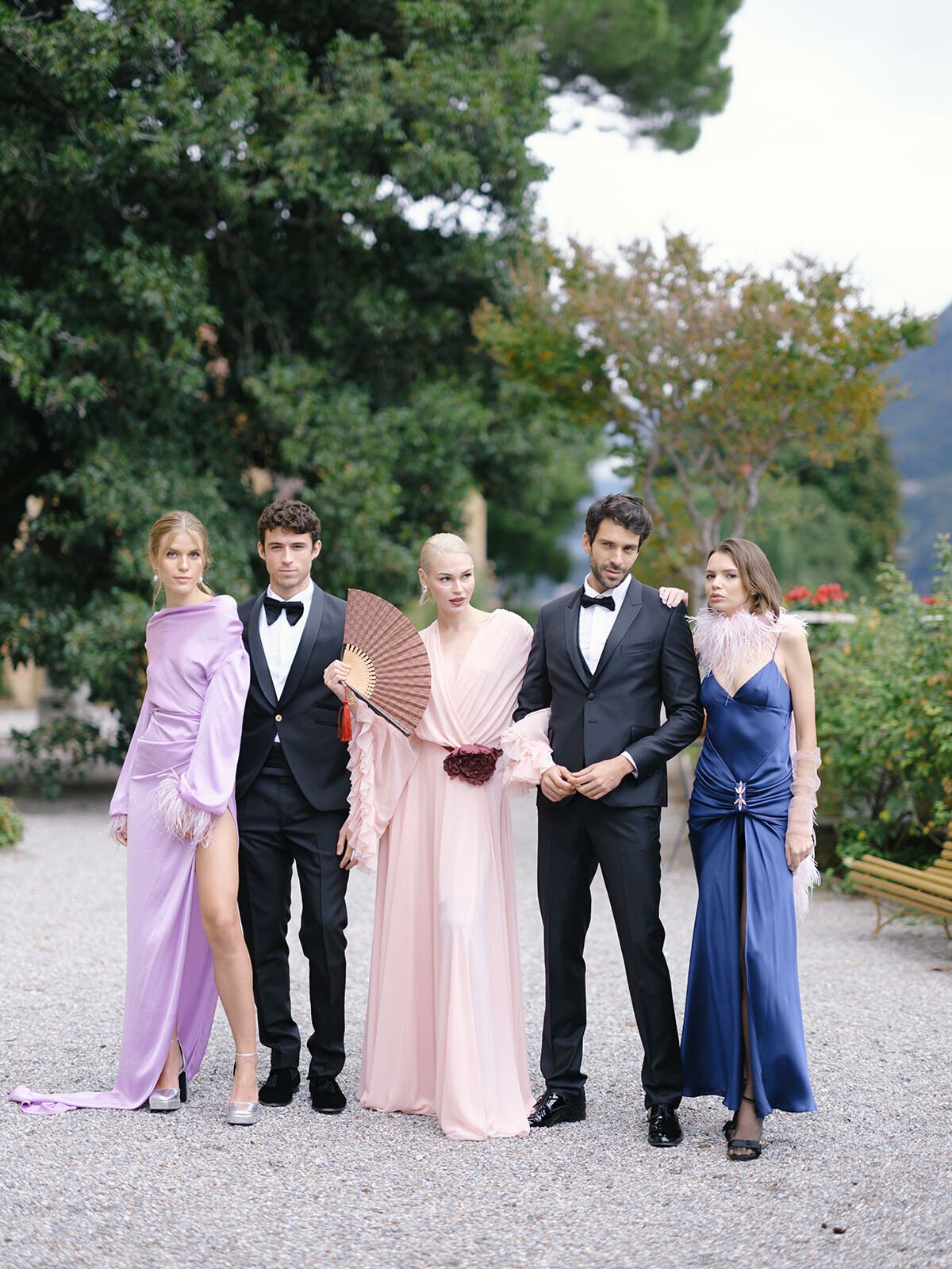 Invitados con vestidos pastel y esmoquin en los jardines junto al lago de Como