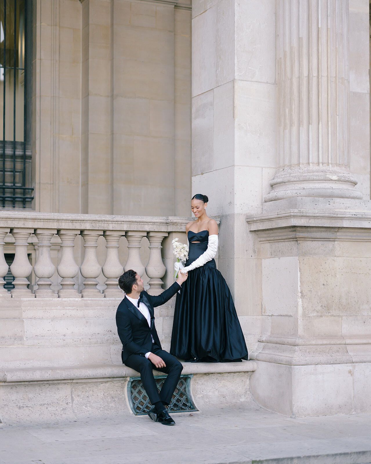 Bräutigam sitzt auf einer Steinbalustrade vor der Braut, Paris