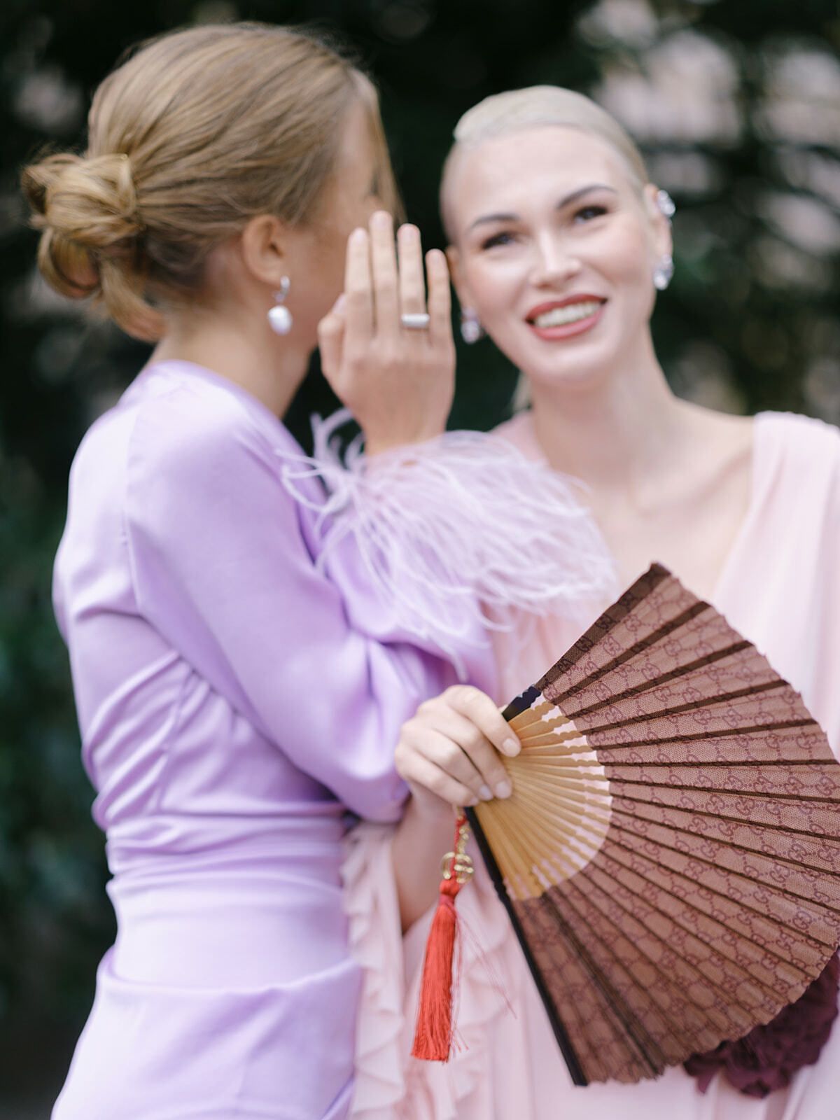 Invitadas riendo con un abanico, moda de boda pastel