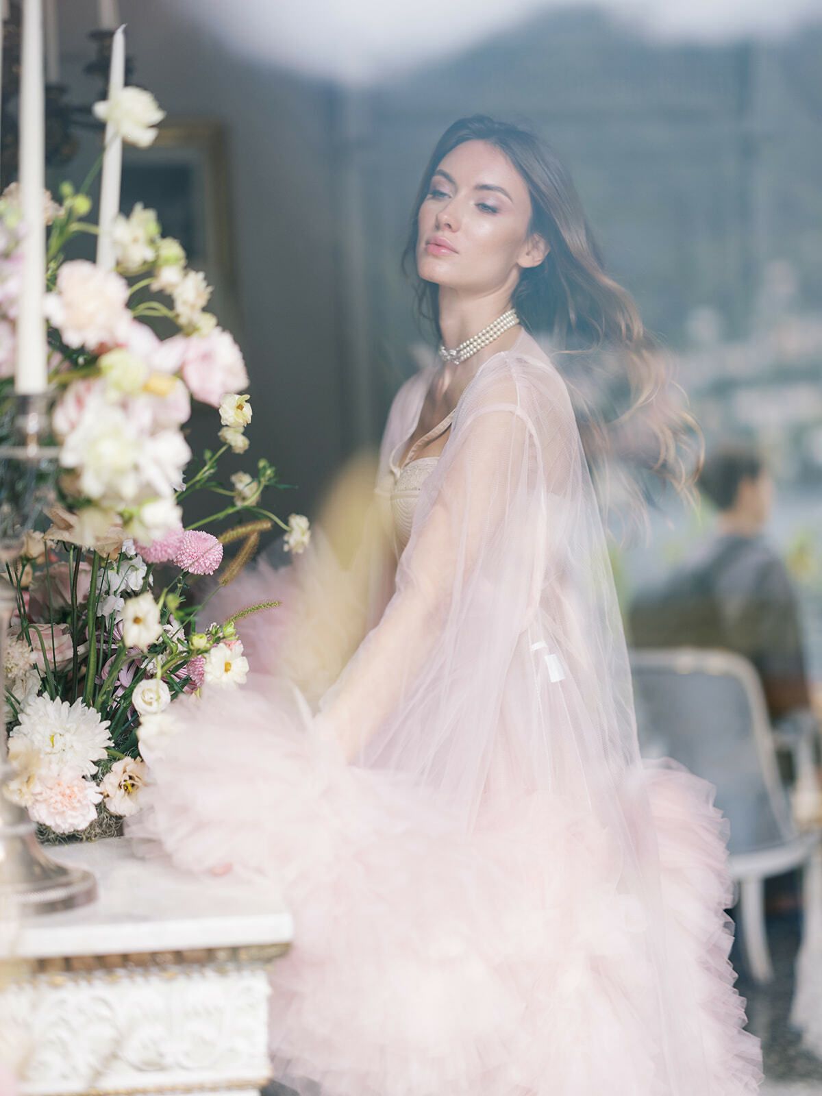 Novia con vestido de plumas rosa empolvado en un salón lleno de flores