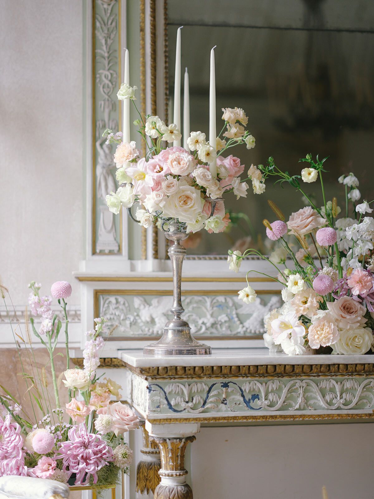 Arreglos florales rosas y velas largas sobre una consola antigua