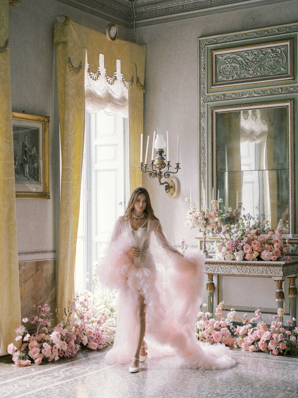 Novia con bata rosa empolvado en una sala llena de flores en Villa Pizzo