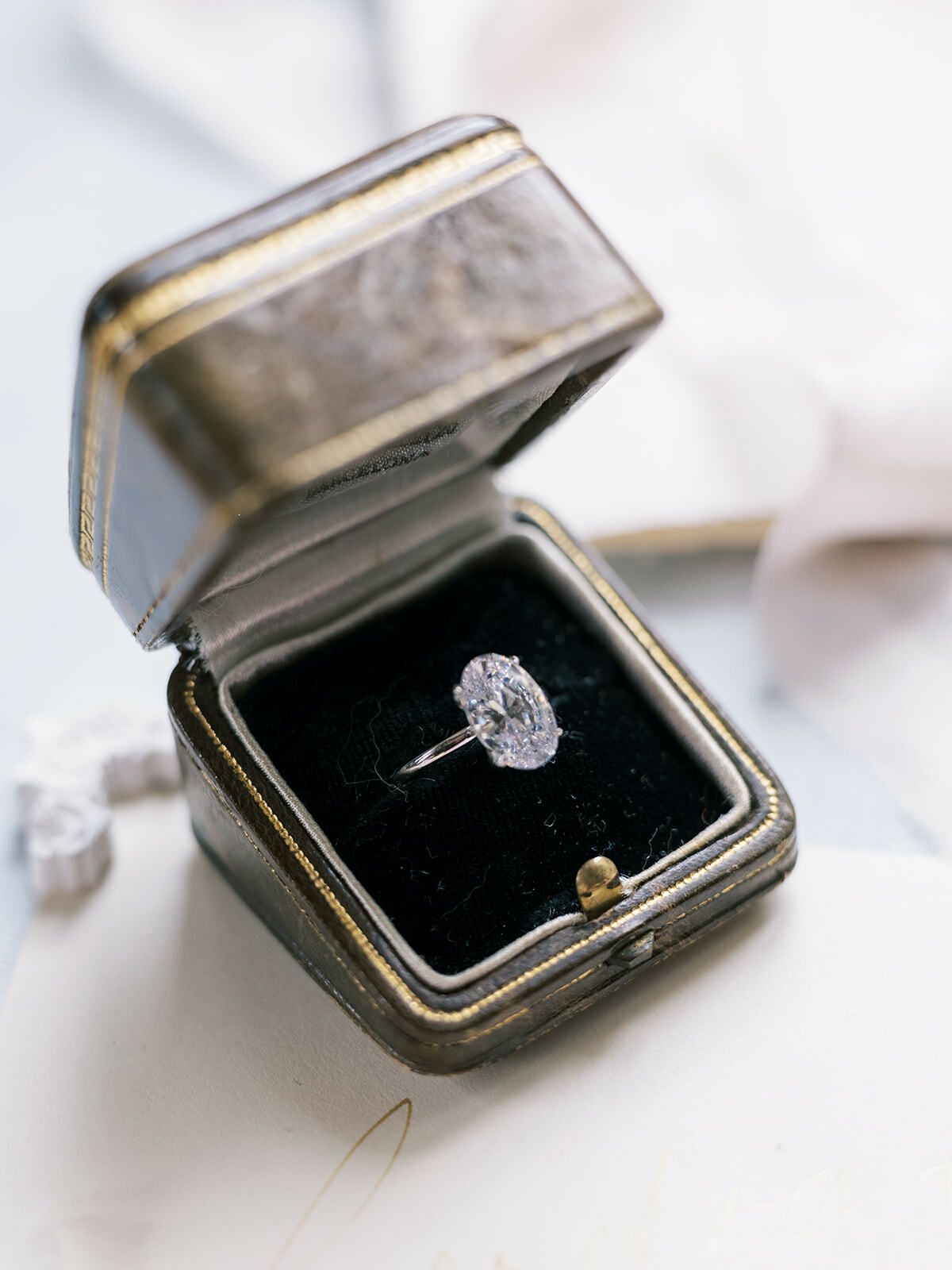 Anillo de compromiso con diamante ovalado en un estuche antiguo