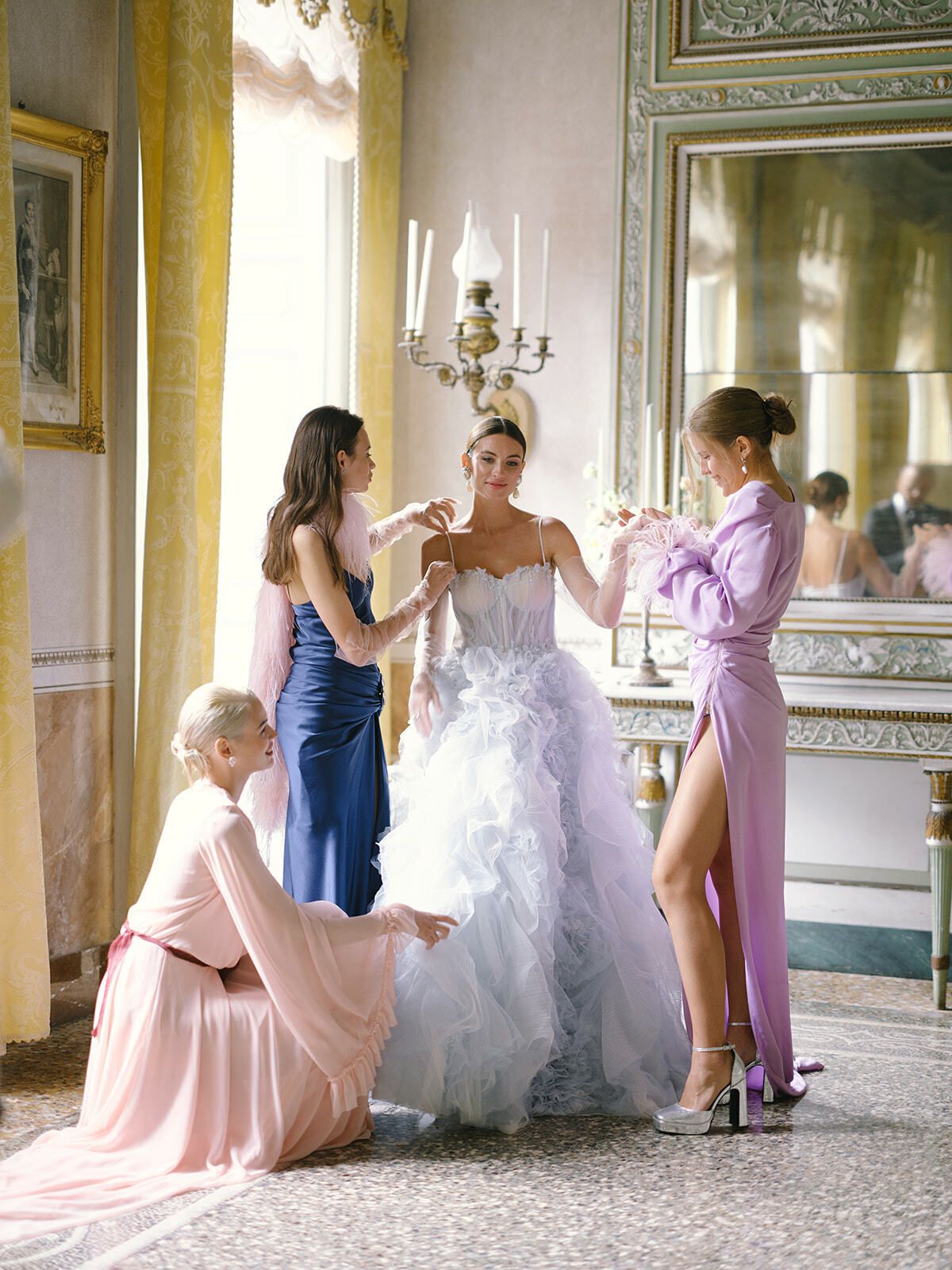 Damas de honor ayudando a la novia a ponerse un vestido de tul azul en Villa Pizzo