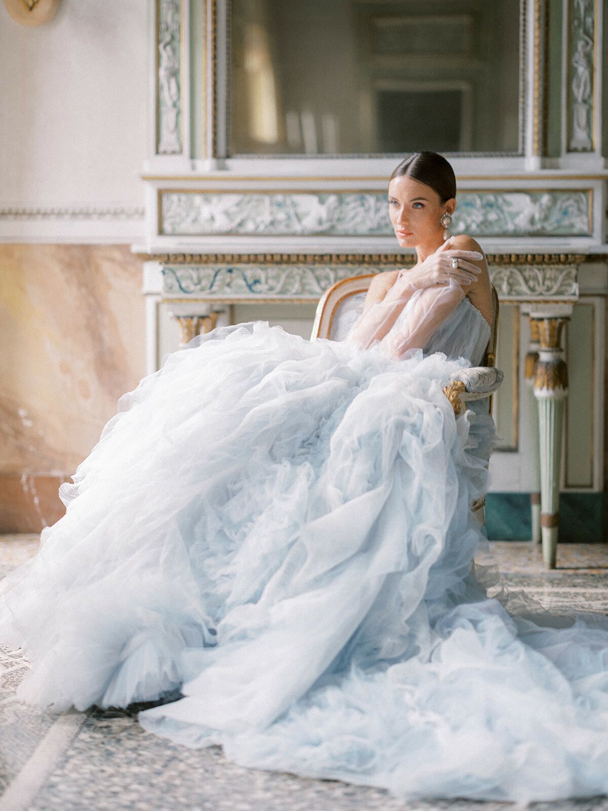 Novia con un voluminoso vestido de tul azul en un salón con frescos