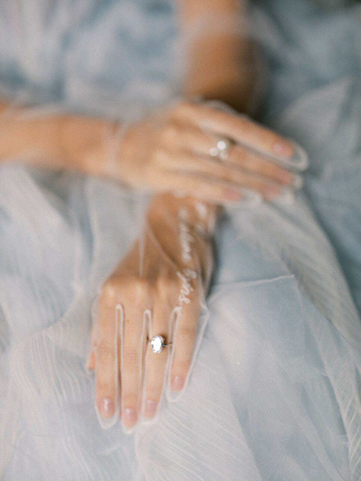 Manos de la novia con anillos sobre una falda de tul azul