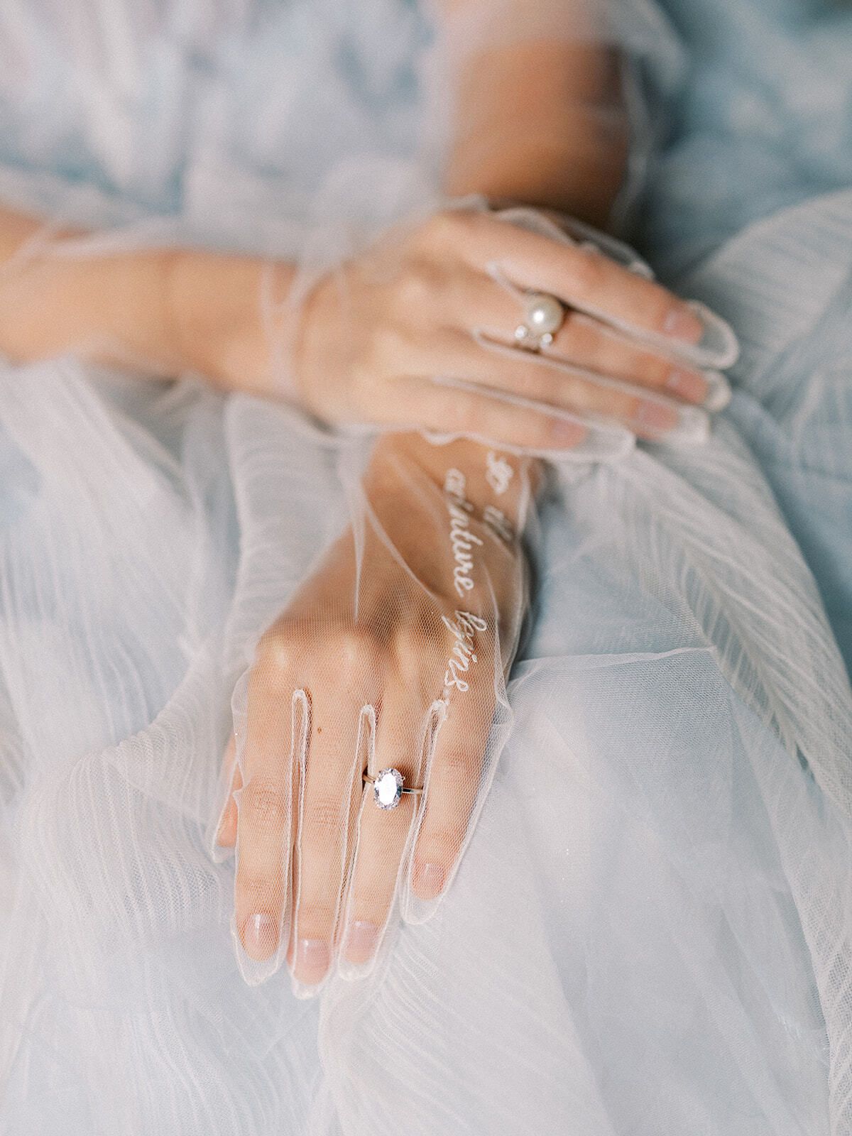 Manos de la novia con anillos sobre tul azul
