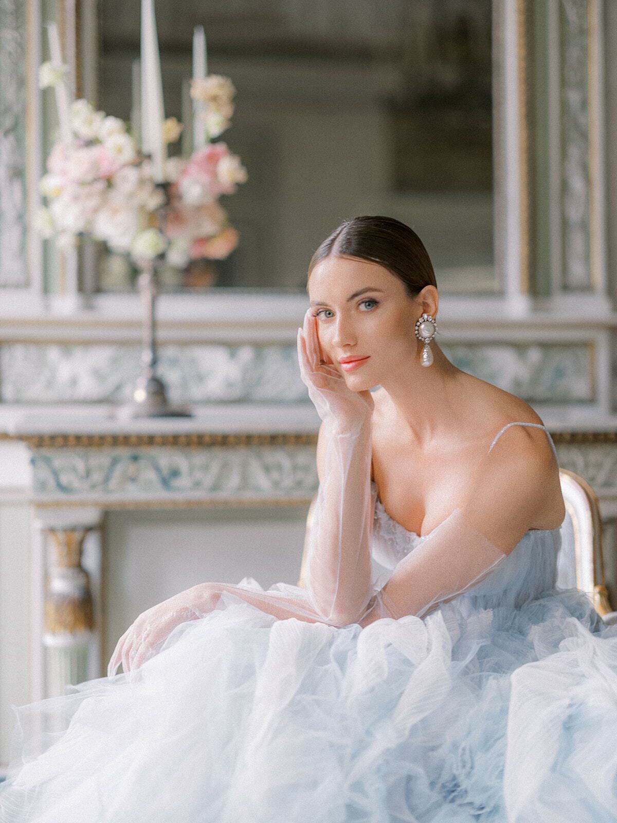 Novia de tul azul sentada ante un espejo iluminado con velas
