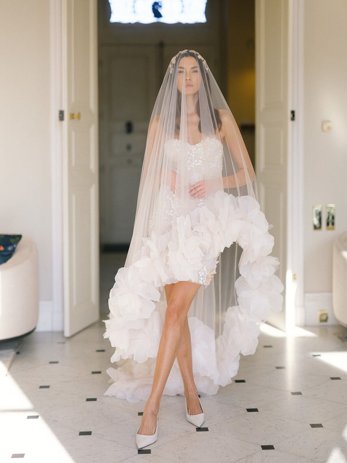 Sposa velata in abito asimmetrico a balze in un corridoio dello château