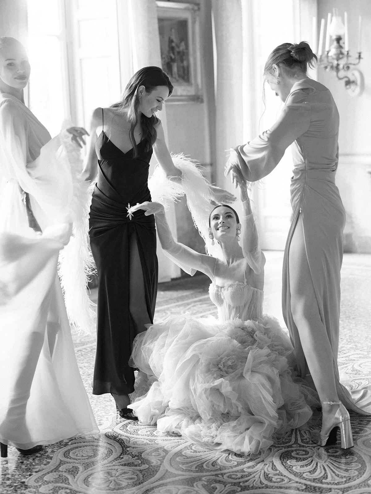 Foto en blanco y negro de las damas de honor ayudando a vestir a la novia
