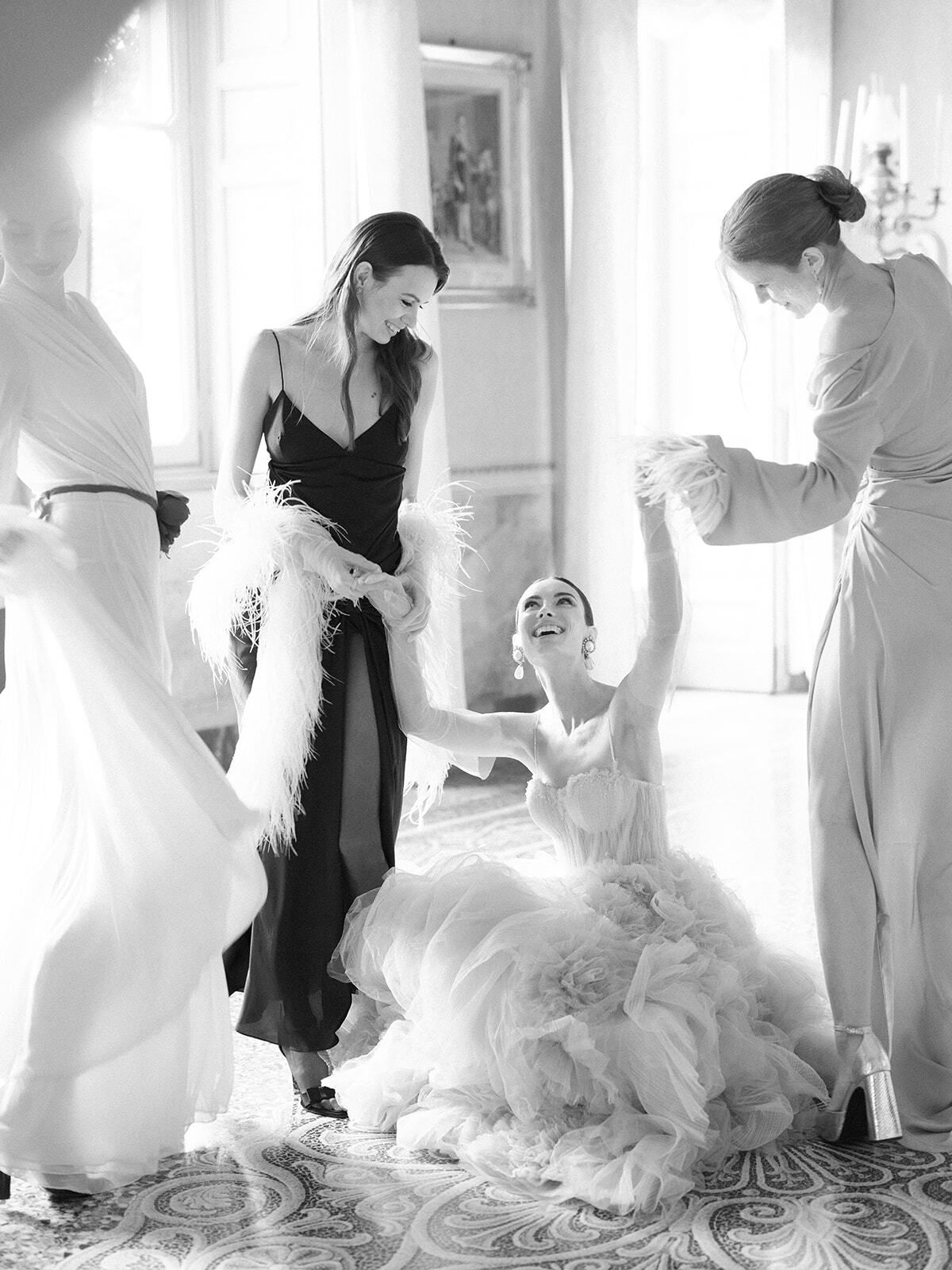 Foto en blanco y negro de las damas de honor ayudando a vestir a la novia