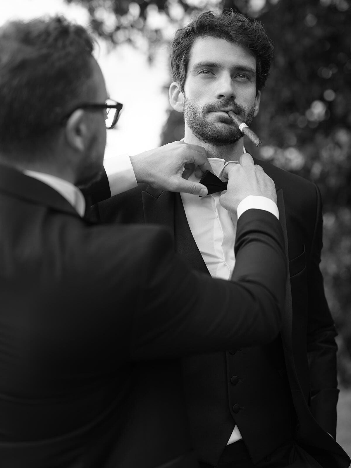 Foto en blanco y negro de un novio al que le ajustan la pajarita