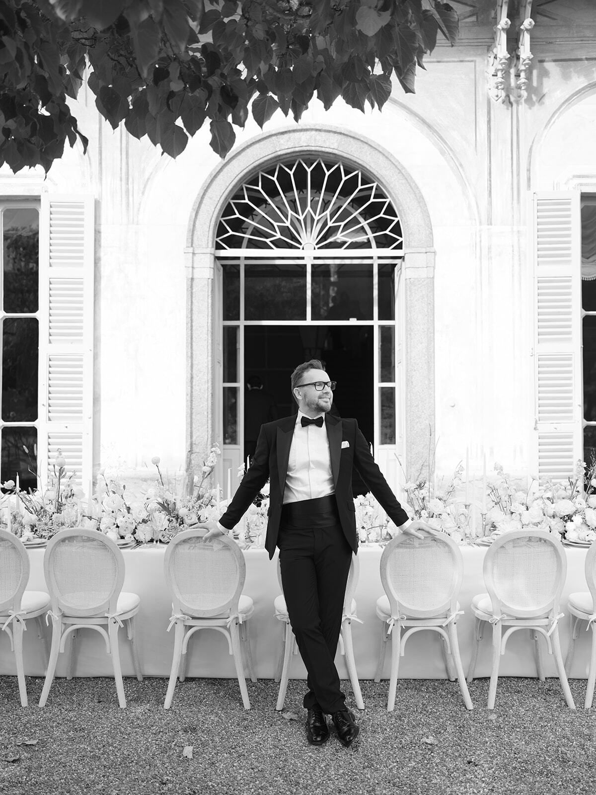 Foto en blanco y negro del novio junto a la mesa del banquete en Villa Pizzo