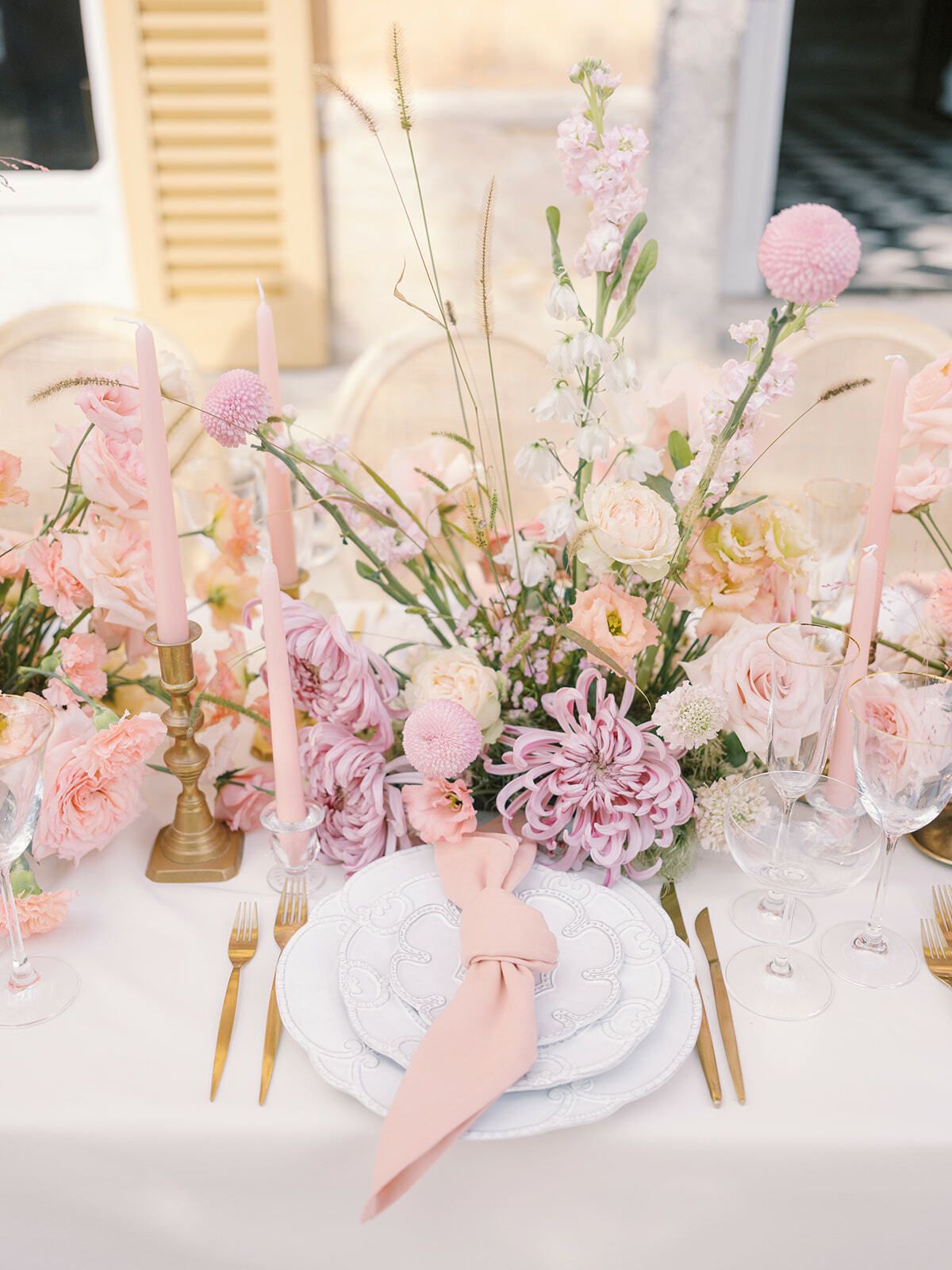 Mesa puesta con servilleta rosa, cubiertos dorados y rosas
