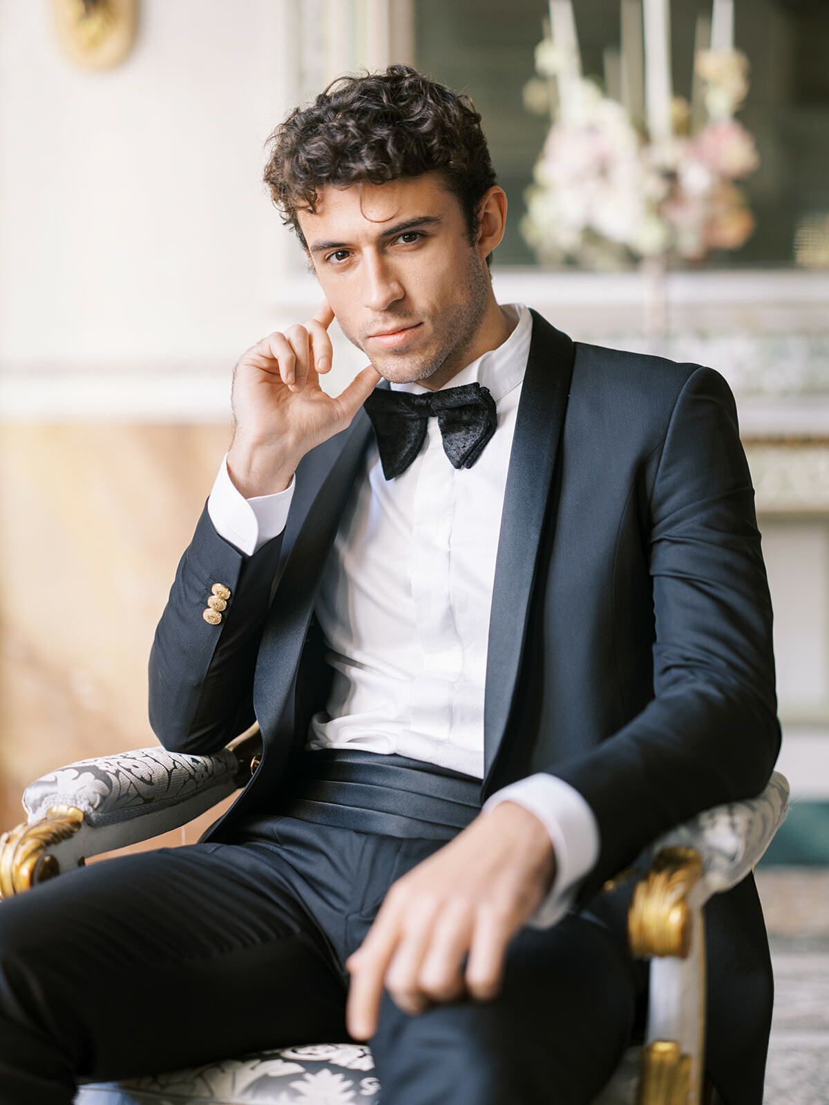 Novio de esmoquin recostado en un sillón dorado