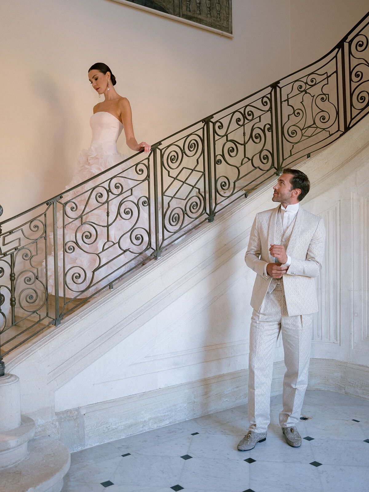 Sposa su una scala in ferro battuto con lo sposo in basso