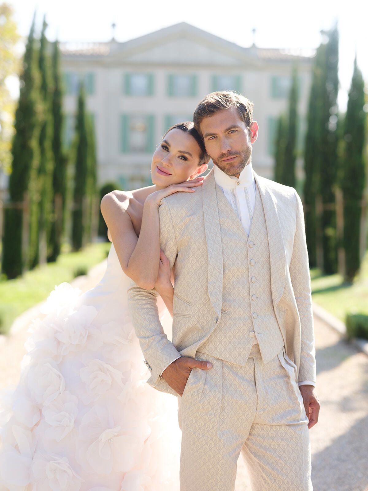 Sposa appoggiata alla spalla dello sposo nel viale di cipressi
