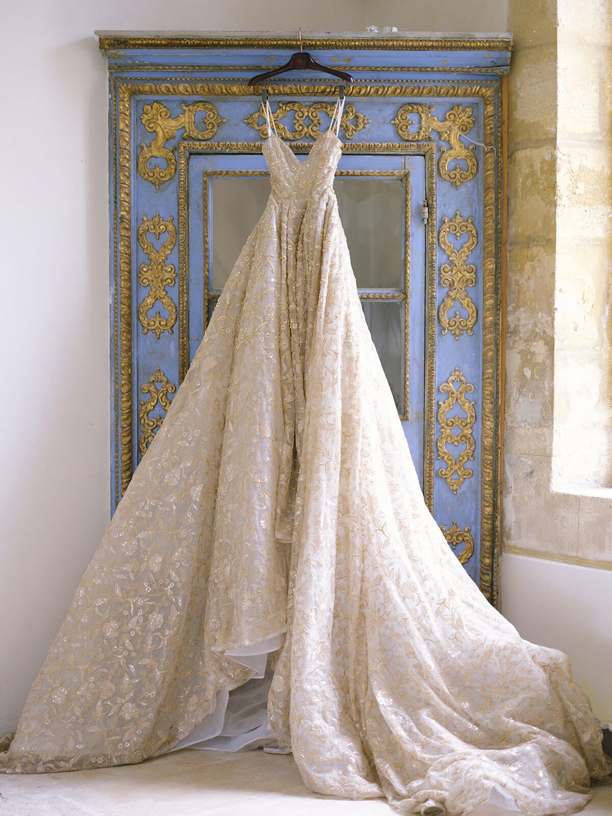 Besticktes Brautkleid an einer antiken blauen Tür
