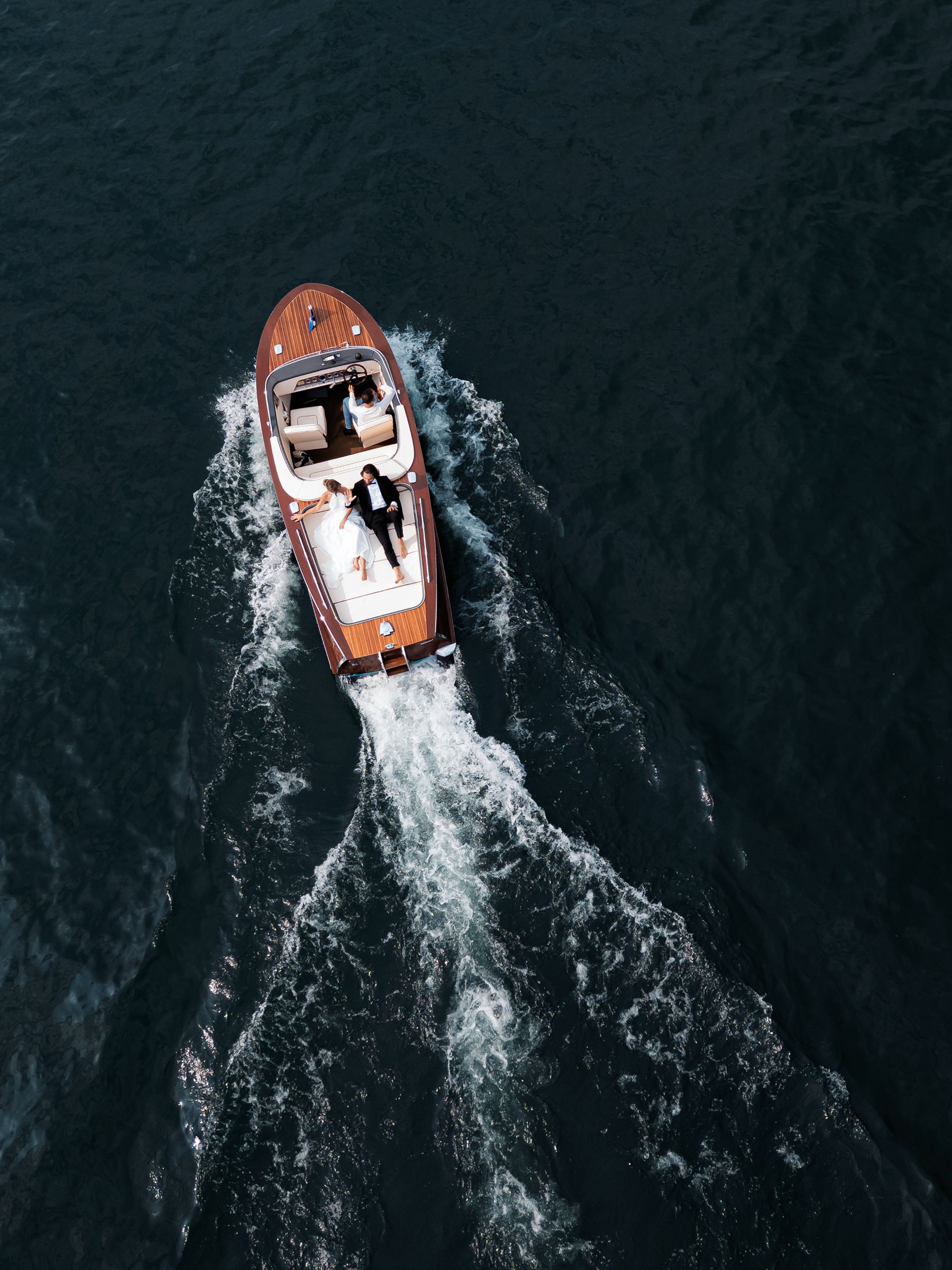 A bride and groom on a wooden boat on Lake Como, seen from above