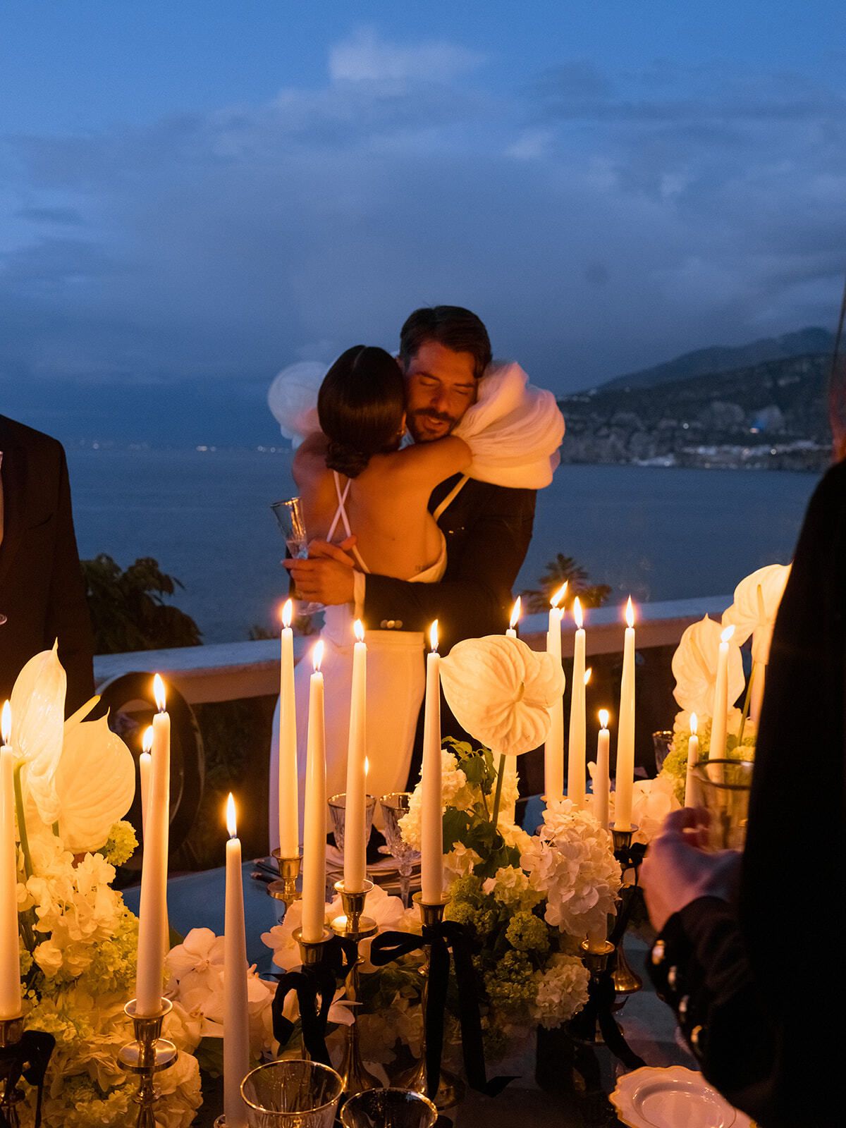 Sposi abbracciati al crepuscolo dietro una tavola a lume di candela, Sorrento